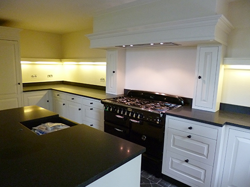 Moderne maatwerk keuken van wit hout met een zwart keukenblad.